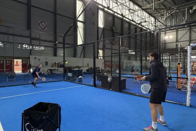 Ciel intérieur d'un court de padel en indoor, deux joueurs en pleine pratique de ce sport de raquette dynamique et convivial.