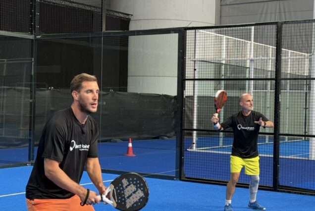 Pratique de padel intérieure avec deux hommes jouant au tennis de paddle sur un court bleu.
