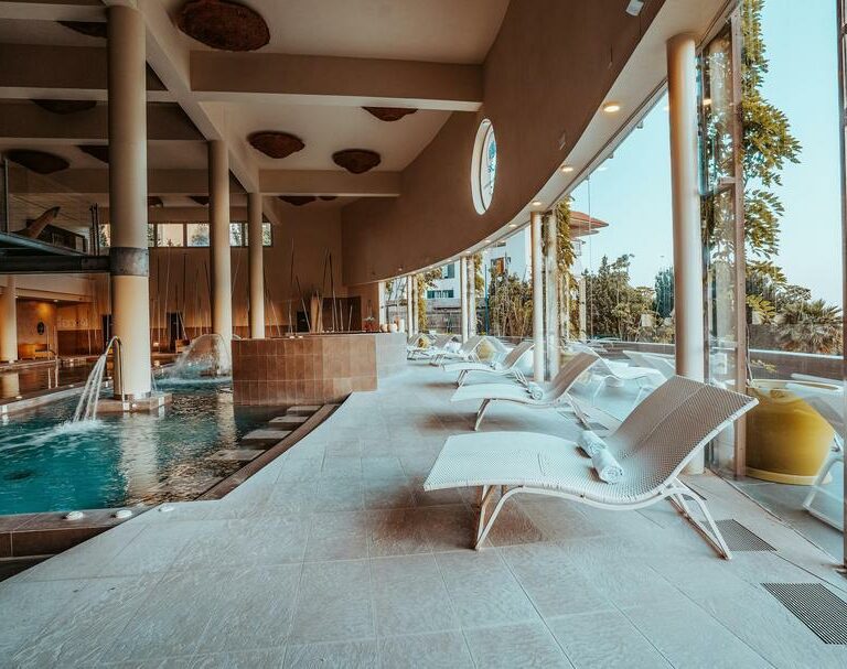 Luxueuse piscine intérieure avec chaise longues, ambiance relaxante et espace détente, idéal pour un moment de bien-être et de loisir dans un centre de sport haut de gamme.