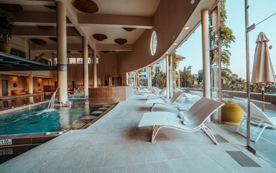 Luxueuse piscine intérieure avec chaise longues, ambiance relaxante et espace détente, idéal pour un moment de bien-être et de loisir dans un centre de sport haut de gamme.